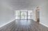 Bright and spacious living room with elegant wood flooring and floor-to-ceiling windows opening to a scenic view.