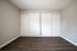 Elegant room with sleek laminate flooring and dual white sliding closet doors, offering ample storage space.