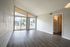 Bright, open living space featuring large windows, vaulted ceiling, and sleek wood flooring, offering a seamless flow to outdoor views.