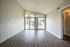 Bright, open living space featuring large windows, vaulted ceiling, and sleek wood flooring, offering a seamless flow to outdoor views.