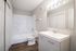 Bright and modern bathroom featuring a sleek vanity, elegant mirror lighting, and a pristine bathtub with contemporary design.