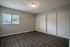 Bright, spacious bedroom with sleek hardwood floors, large window, and ample closet space featuring elegant white doors.