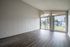Bright and airy living room with modern flooring, large windows, and a serene outdoor view.