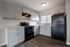 Modern kitchen with sleek cabinets, black appliances, and large window for natural light.