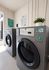 Modern laundry room with sleek coin-operated washers, bright natural light, and a touch of greenery.