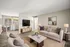 Bright, modern living room in an elegant apartment featuring cozy beige seating, a sleek entertainment center, and a charming dining area by a sunny window.