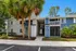 Charming blue and gray apartment building with lush landscaping and palm trees, inviting entrance, and balcony views.