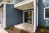 Inviting apartment entrance with modern blue siding and spacious front patio, promising a warm welcome.