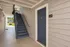 Inviting apartment entrance with stylish blue door and sunny outdoor stairs, showcasing modern charm and convenient access.