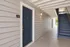 Inviting apartment entrance with elegant blue door and neatly painted siding, complemented by ambient lighting and a nearby staircase offering easy access.