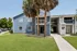 Charming blue apartment building with lush green lawn and elegant palm trees, offering a welcoming and serene living environment.