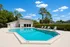 Inviting outdoor pool with sleek lounge chairs surrounded by lush greenery and clear blue skies.