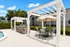 Inviting outdoor barbecue area with stylish pergola, elegant dining set, and modern grills beside a serene pool.