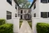 Charming courtyard entrance of a modern apartment complex, featuring sleek black accents and lush greenery.