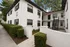 Charming multi-level white brick apartment building with lush landscaping and modern black accents, perfect for stylish urban living.