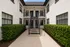 Charming apartment entrance with lush greenery, modern black railing, and stylish facade.