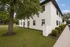 Charming apartment building with a lush green lawn and elegant white exterior, perfect for a serene living experience.