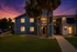 Charming apartment complex showcasing sunset ambiance and inviting exterior lighting, nestled amidst lush greenery and towering palms.