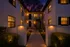 Charming apartment complex at twilight, featuring warm illuminated windows, elegant pathway lighting, and inviting entryway.