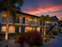 Charming apartment building exterior at sunset, featuring lush landscaping and inviting warm lighting.