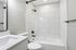 Elegant bathroom with sleek white tiles, modern black fixtures, and a pristine countertop.