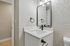Modern bathroom with elegant black fixtures, a large mirror, and a sleek white vanity with textured walls.