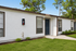 Charming single-story apartment with pristine white exterior and lush green lawn, perfect for tranquil living.