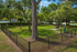 Charming fenced green space with lush trees and a welcoming bench, perfect for your pup to play!
