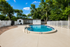 Charming outdoor pool with crystal clear water, surrounded by lush greenery and a white picket fence, perfect for relaxation and leisure.