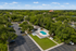 Aerial view of a charming apartment complex surrounded by lush greenery, featuring a pristine swimming pool, ample parking, and serene outdoor spaces perfect for relaxation.
