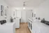 Bright and spacious laundry room featuring multiple washing and drying machines, modern laminate flooring, and ample natural light.