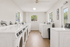 Bright and spacious laundry room with modern washers and dryers, featuring large windows and sleek wooden floors.