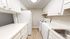 Modern kitchen with sleek white cabinetry, spacious countertops, and essential appliances including fridge and stove.