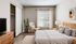 Bright and inviting bedroom with elegant decor, wooden accents, and a cozy reading nook by the window.