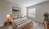 Bright and inviting bedroom with modern wooden furniture, cozy bedding, and large window flooding the space with natural light.