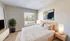 Bright and cozy bedroom featuring a large window, stylish decor, and modern furniture, offering a serene and inviting atmosphere.