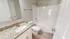 Elegant bathroom with stylish granite countertop, spacious white bathtub, and sleek wood flooring.