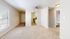Bright and airy apartment interior featuring a cozy living room with plush carpet, large window for natural light, and an adjacent modern kitchen with sleek appliances.