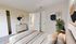 Modern bedroom with minimalist decor, featuring a cozy bed, stylish dresser, and abstract wall art.