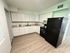 Modern kitchen featuring sleek black appliances, elegant white cabinetry, and stylish marble countertops.