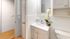 Bright and modern bathroom featuring sleek white cabinetry, elegant fixtures, and a decorative orchid accent.