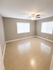 Bright and spacious room with elegant tile flooring, neutral walls, and large windows complemented by a modern ceiling fan.