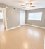 Bright, spacious bedroom featuring elegant tile flooring, a large window with blinds, and a ceiling fan.