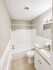 Modern bathroom featuring a sleek bathtub, elegant granite countertop, and bright vanity lighting.