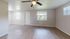 Bright and airy living room featuring elegant wood flooring, large windows, and a modern ceiling fan.