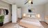 Inviting bedroom with cozy beige bedding, modern wooden furniture, and ambient lighting, complemented by a stylish open closet and chic artwork.