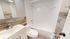 Modern bathroom featuring a sleek vanity, elegant wood-accented walls, and a pristine bathtub with bright tiles.