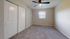 Bright and cozy bedroom with plush carpet, stylish ceiling fan, and ample closet space, offering a serene and inviting atmosphere.