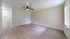 Spacious living room with modern ceiling fan, bright hardwood flooring, and ample natural light.