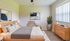 Bright and inviting bedroom featuring a cozy double bed, stylish decor, and ample natural light from large windows.